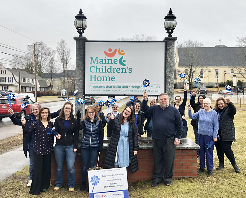 The staff of Maine Children's Home standing in front of the Maine Children's Home street sign.
