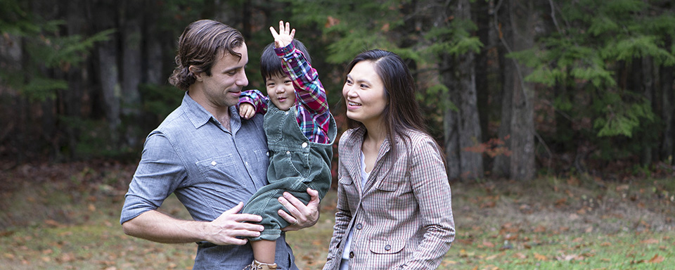 A toddler son waves at the camera while being held by his father.