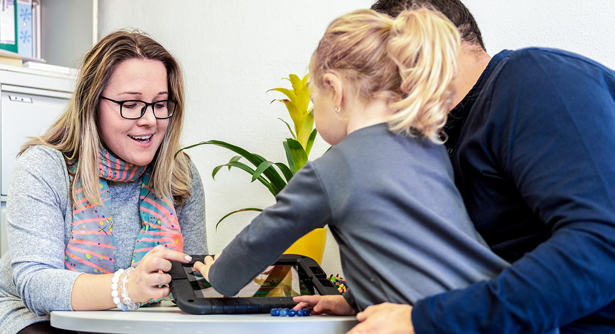 Social worker using a tablet with a little girl and the girl's father