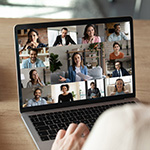 A person signs on a video conference on their laptop.